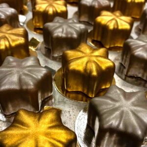 Nyårstjärna- Trompe l'oeil fruktbakelse. Fylld med chokladmousse och salt karamel doppad i mjölkchoklad. Det här är garanterat den godaste stjärna du någonsin smakat. Vi har gjort den superpopulära virala bakelsen i nyårsskrud