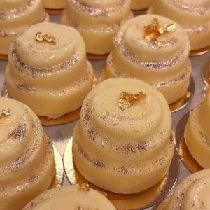 Nyårsbakelse- Trompe l'oeil fruktbakelse. Fylld med bubblande champagnemousse, yuzukräm och smultroncoulis doppad i vit choklad.